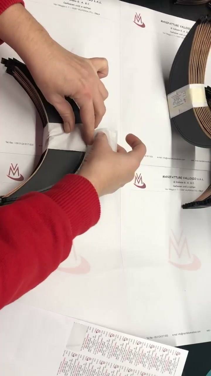 Mani al banco mentre preparano le visiere sulla carta intestata Manifatture Vallosio